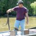 A tour guide in a swamp boat holding a large snake.
